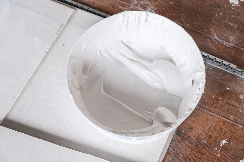 White wall repair putty container resting on cut drywall panels.