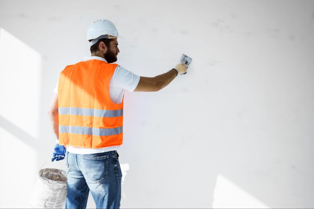Commercial painting contractor smoothing indoor wall plaster during surface preparation