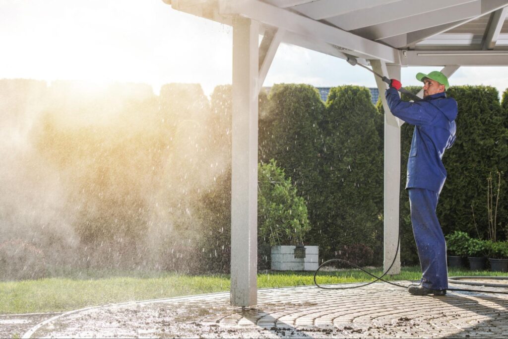 A hired cleaner uses a power wash to clean the patio.