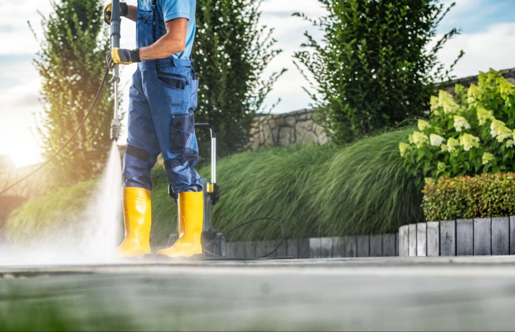 A gardener uses a power wash to clean the patio.