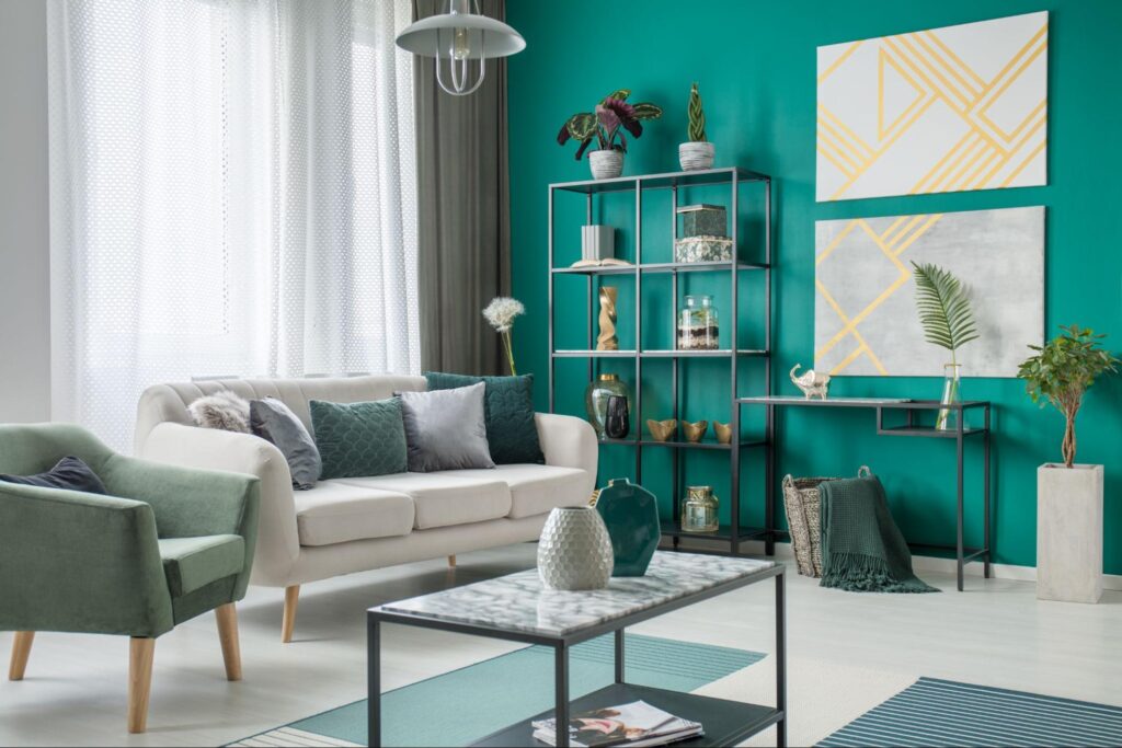 A living room with a soft green and white sofa and decor, styled against a rich green accent wall.