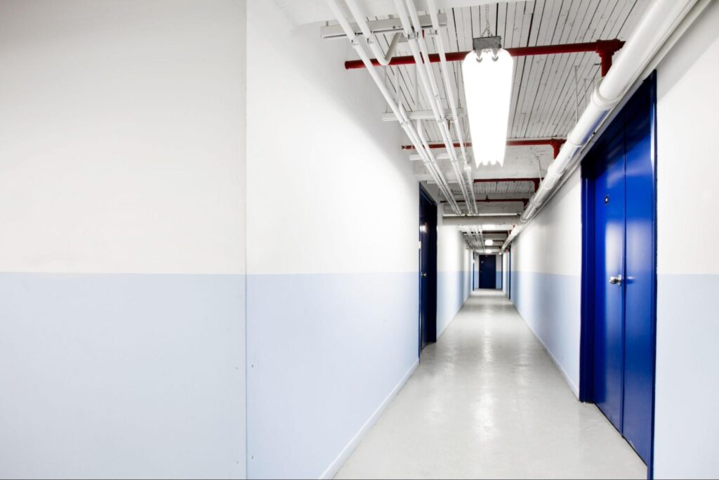 Long blue corridor with white commercially painted walls and a royal blue door.