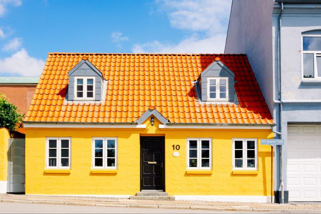 Exterior home painting of a colorful one-story brick house finished in bright yellow.